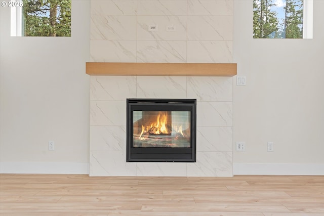 interior details with baseboards, wood finished floors, and a tile fireplace