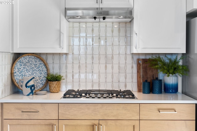 kitchen with light brown cabinetry, tasteful backsplash, stainless steel gas stovetop, and exhaust hood