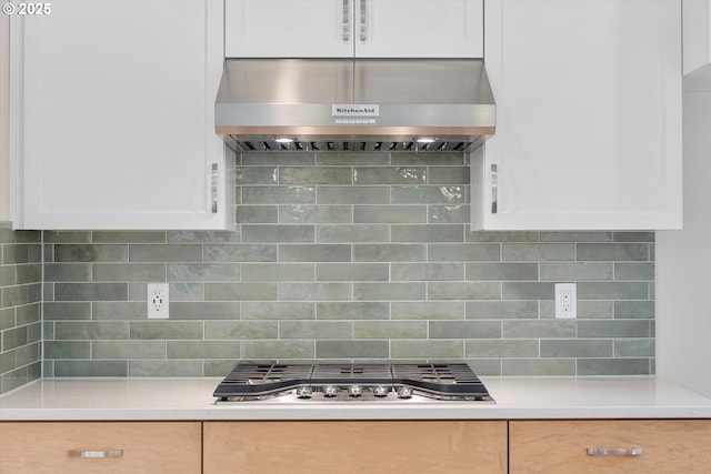 kitchen featuring stainless steel gas cooktop, light countertops, decorative backsplash, white cabinetry, and exhaust hood