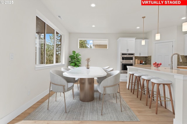 dining area featuring light wood-type flooring, baseboards, visible vents, and recessed lighting