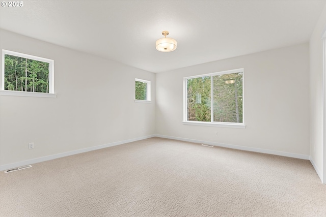 unfurnished room featuring baseboards, visible vents, and light colored carpet