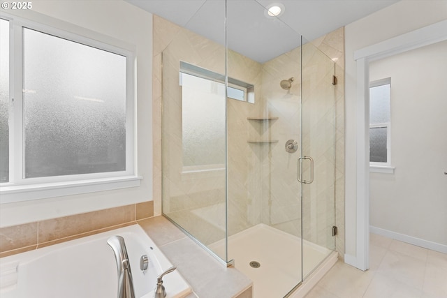 full bathroom featuring tile patterned flooring, a garden tub, a shower stall, and baseboards