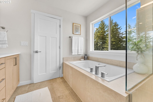 bathroom featuring tile patterned flooring, vanity, and tiled tub