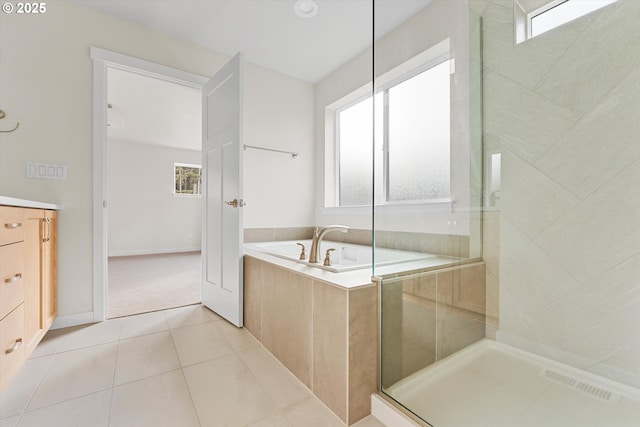 bathroom with tile patterned flooring, a healthy amount of sunlight, a tile shower, and a bath