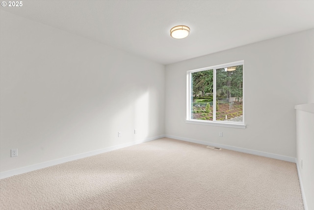 spare room with light carpet, baseboards, and visible vents