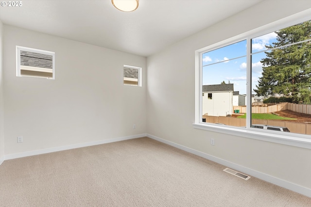 unfurnished room with baseboards, visible vents, and light colored carpet