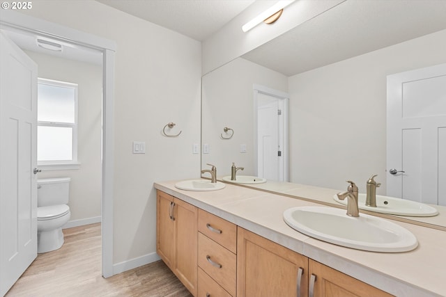 full bath with a sink, toilet, and wood finished floors