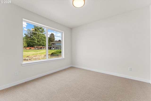 spare room featuring light carpet and baseboards