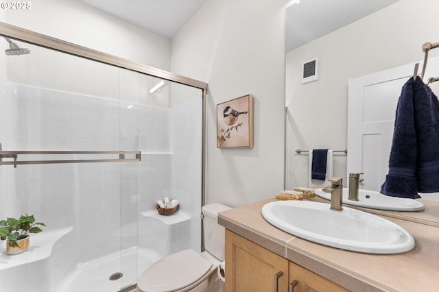 bathroom featuring vanity, a shower with shower door, and toilet