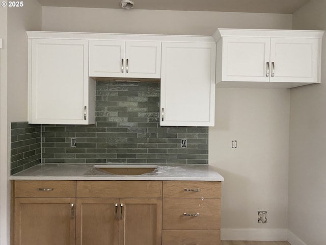 kitchen with decorative backsplash, wood-type flooring, white cabinetry, and sink