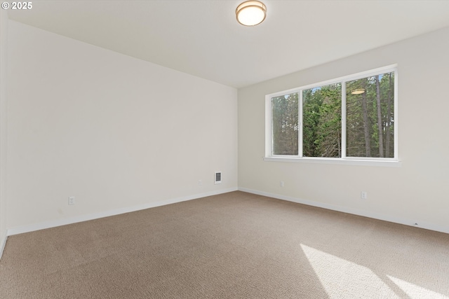 spare room featuring carpet flooring, visible vents, and baseboards