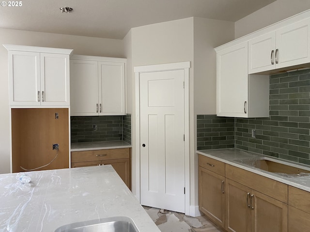 kitchen with white cabinets, tasteful backsplash, and light stone countertops