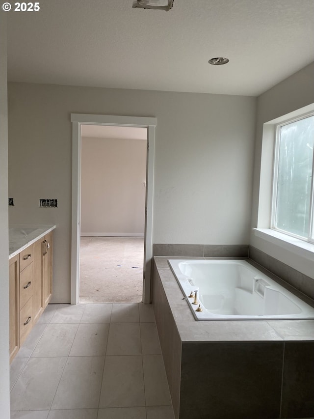 bathroom featuring tile patterned floors, vanity, and a relaxing tiled tub