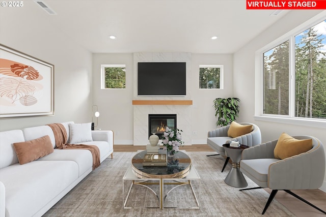 living area with baseboards, visible vents, a tiled fireplace, and recessed lighting