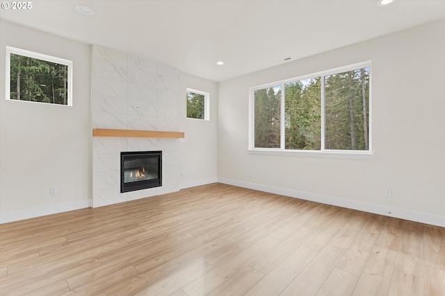 unfurnished living room with a tile fireplace, recessed lighting, wood finished floors, visible vents, and baseboards