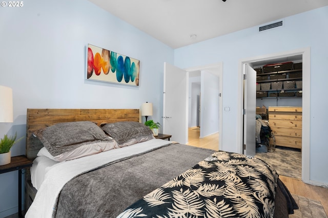 bedroom with a walk in closet, light wood-type flooring, and a closet