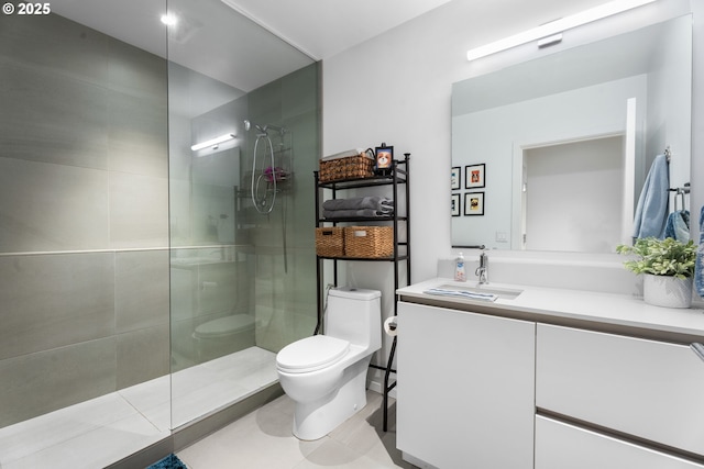 bathroom with toilet, tiled shower, and vanity