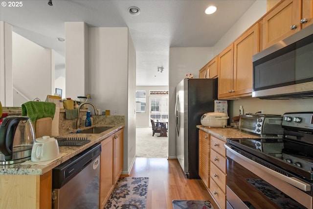 10238 NE Snoqualmie St, Hillsboro, OR 97006 - kitchen featuring appliances with stainless steel finishes, a sink, light wood finished floors, light stone countertops, and recessed lighting
