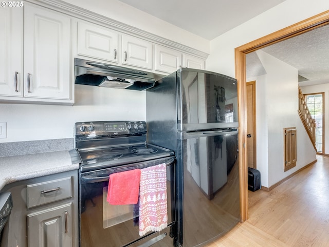 611 NW 4th Pl, Battle Ground, WA 98604 - kitchen with under cabinet range hood, range with electric stovetop, light wood finished floors, and white cabinets