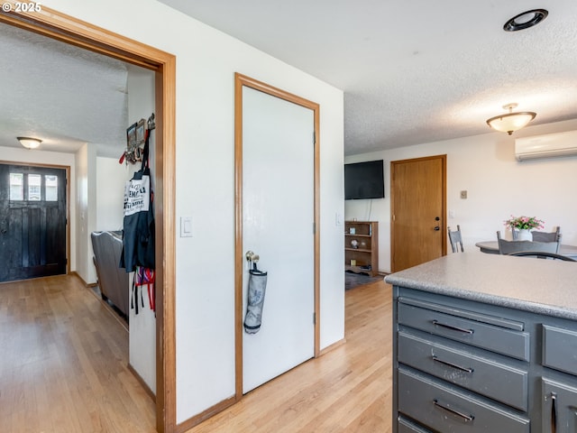 611 NW 4th Pl, Battle Ground, WA 98604 - kitchen featuring gray cabinets, a wall unit AC, a textured ceiling, light wood-style flooring, and light countertops