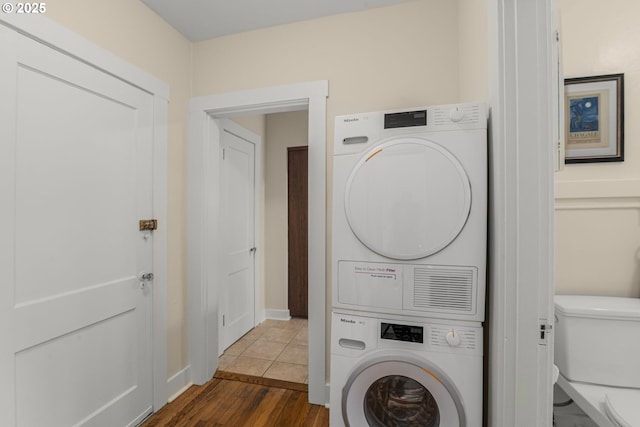 laundry room featuring stacked washer / dryer and wood finished floors