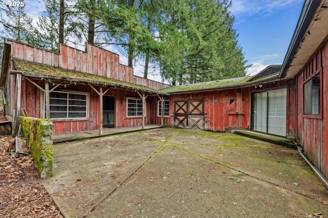 rear view of property featuring board and batten siding, an exterior structure, and an outdoor structure