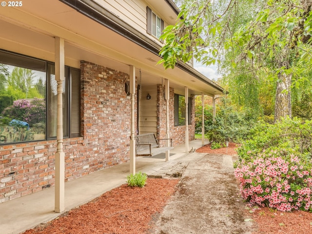 property entrance featuring covered porch and brick siding