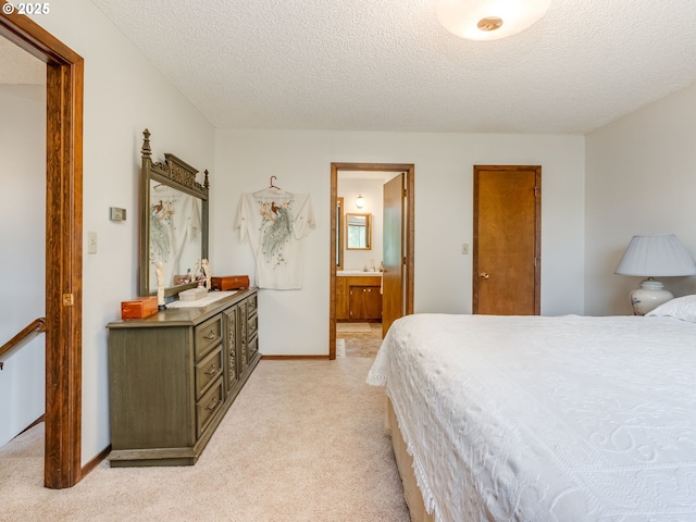 bedroom with light colored carpet, a textured ceiling, ensuite bath, and baseboards