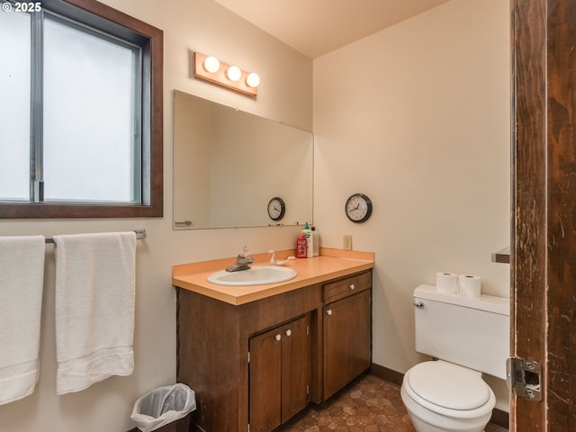 bathroom featuring toilet, baseboards, and vanity