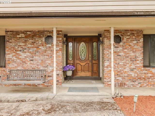 property entrance with brick siding and a porch
