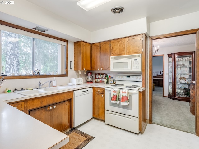 kitchen with white appliances, a sink, brown cabinetry, light countertops, and light floors