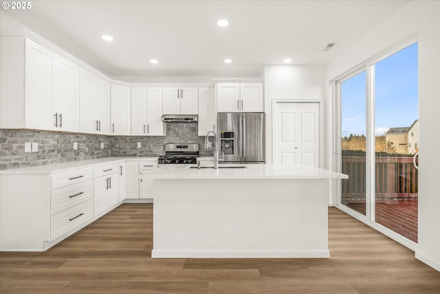 kitchen featuring stainless steel appliances, a center island with sink, and white cabinets