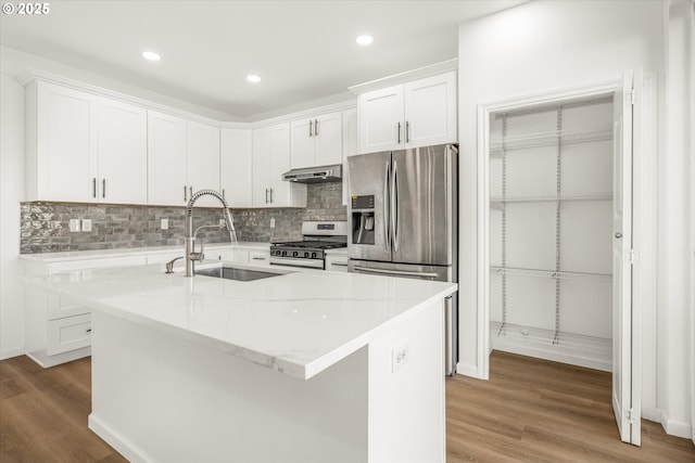 kitchen with sink, hardwood / wood-style floors, stainless steel appliances, white cabinets, and a center island with sink