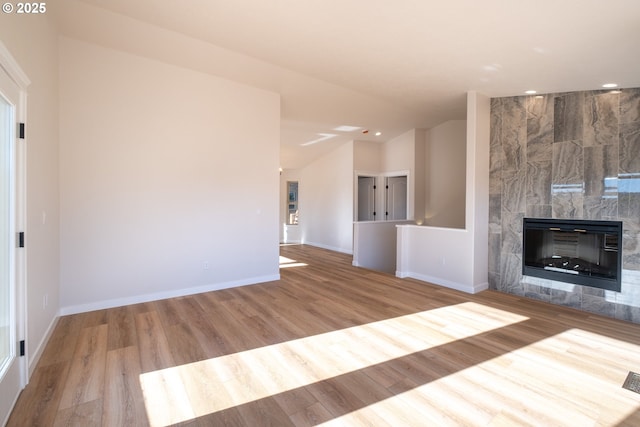 unfurnished living room with lofted ceiling, a fireplace, and light hardwood / wood-style floors