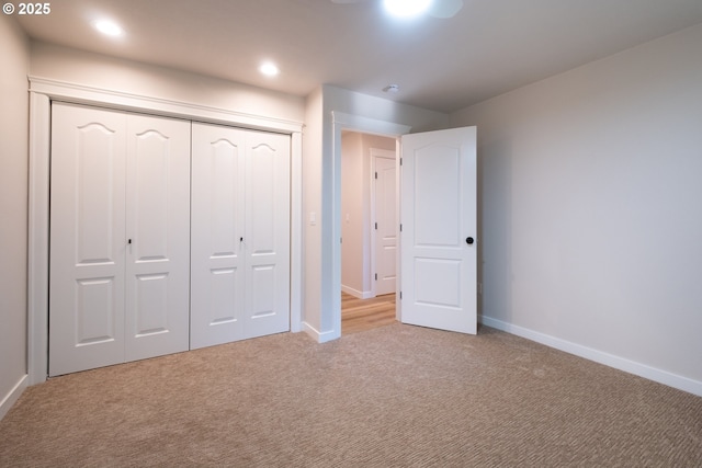 unfurnished bedroom featuring light carpet and a closet