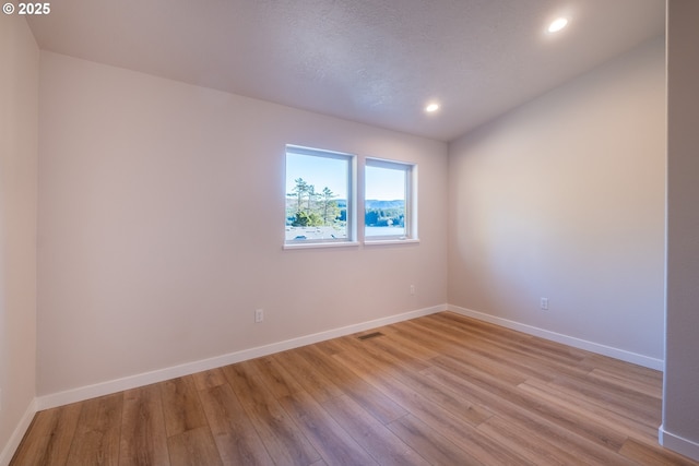 unfurnished room with light hardwood / wood-style flooring and a textured ceiling