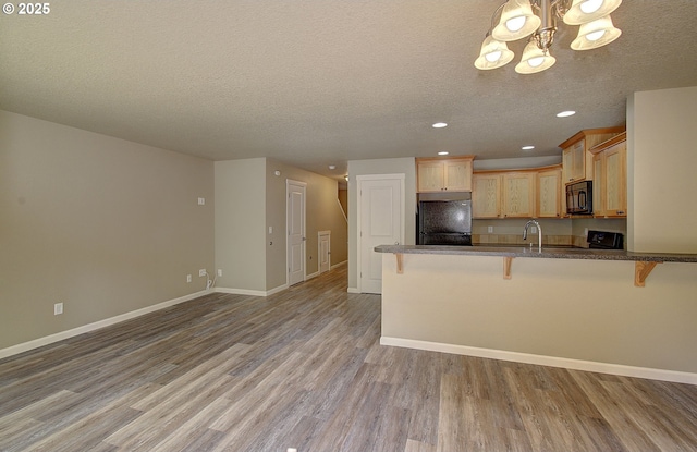 9513 NE 73rd St, Vancouver, WA 98662 - kitchen with black microwave, refrigerator, light wood-style flooring, a breakfast bar area, and a peninsula