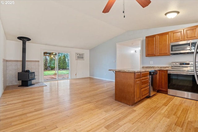 kitchen with appliances with stainless steel finishes, a wall mounted air conditioner, kitchen peninsula, light hardwood / wood-style flooring, and ceiling fan