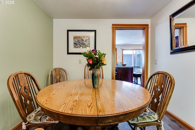 dining area with dark wood-type flooring and baseboards