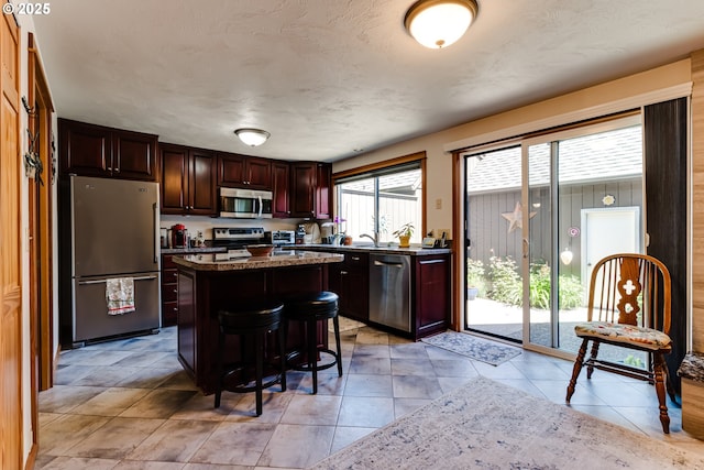 kitchen featuring stainless steel appliances, a kitchen island, a breakfast bar, and dark brown cabinets