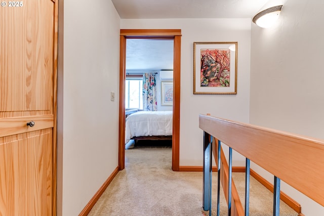 hallway featuring light carpet, baseboards, an upstairs landing, and a wall unit AC