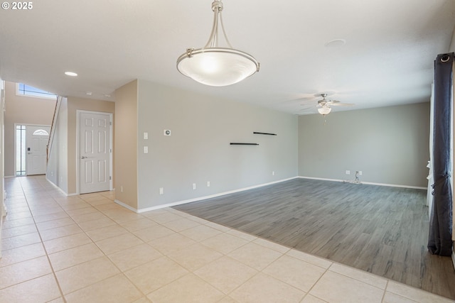 unfurnished living room with light tile patterned flooring, baseboards, and ceiling fan