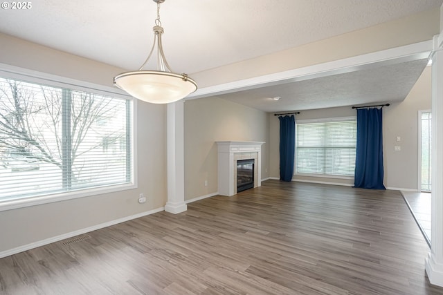 unfurnished living room with wood finished floors, a healthy amount of sunlight, and a tile fireplace