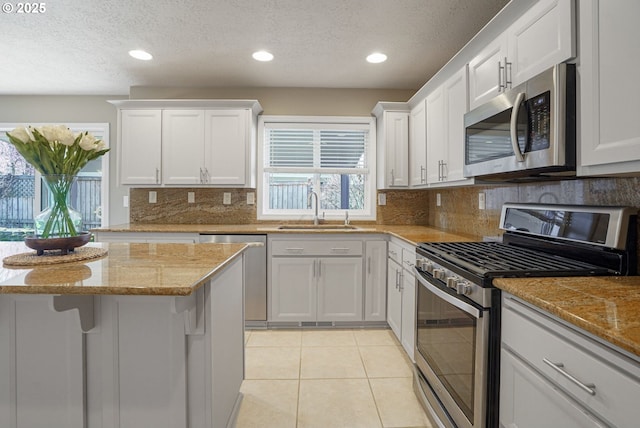 kitchen featuring light tile patterned flooring, white cabinets, appliances with stainless steel finishes, and a sink