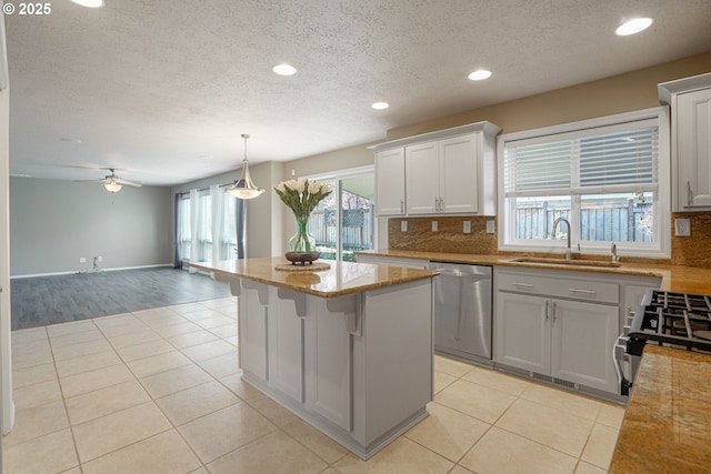 kitchen featuring light tile patterned floors, a kitchen island, appliances with stainless steel finishes, and a sink