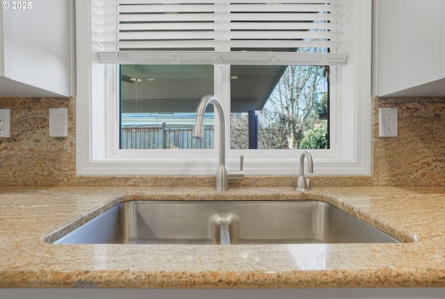 interior details featuring light stone counters, decorative backsplash, and a sink