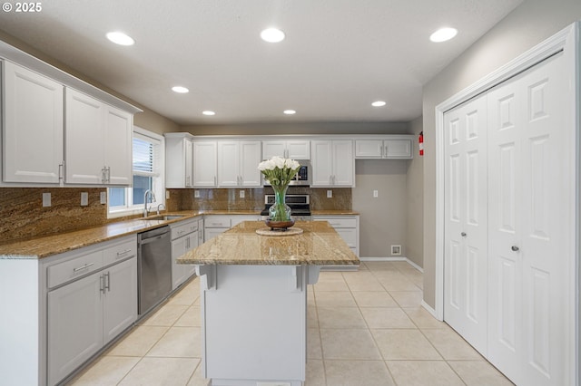 kitchen featuring light tile patterned floors, appliances with stainless steel finishes, a kitchen island, and a sink