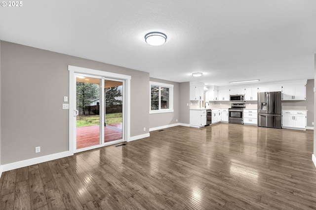 unfurnished living room featuring dark wood-type flooring and a textured ceiling