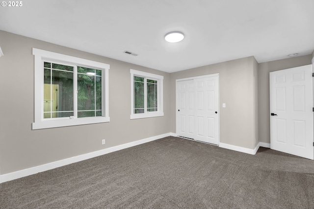 spare room featuring dark colored carpet