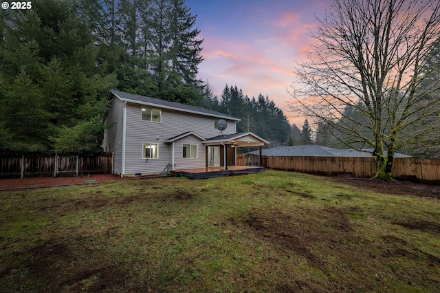 back house at dusk with a deck and a yard